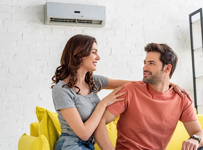 couple sitting underneath a mini-split air conditioner