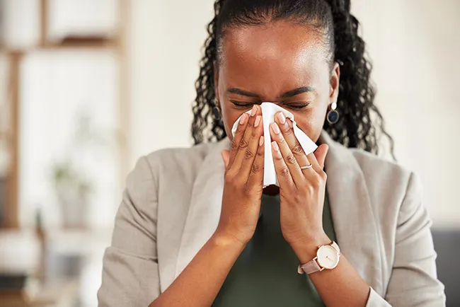 woman sneezing because of poor indoor air quality.