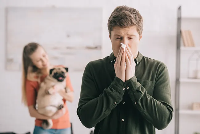 a man sneezing because of indoor allergies.